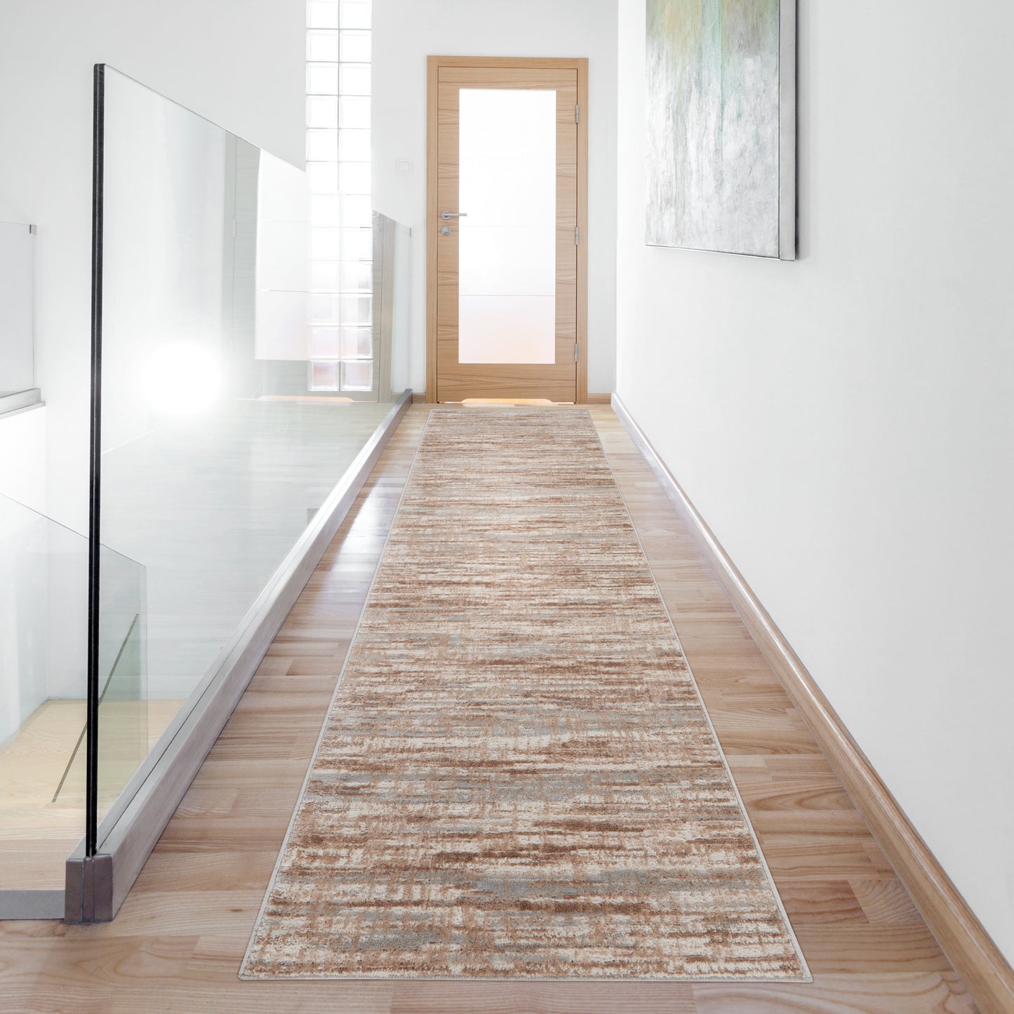 Long beige runner rug with subtle pattern in a bright hallway with glass railing and a wooden door at the end.