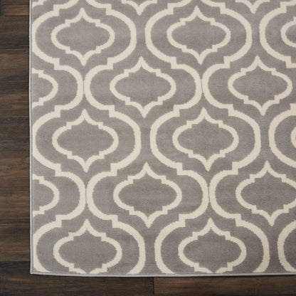 Gray rug with white interlocking trellis motif on dark wood floor.