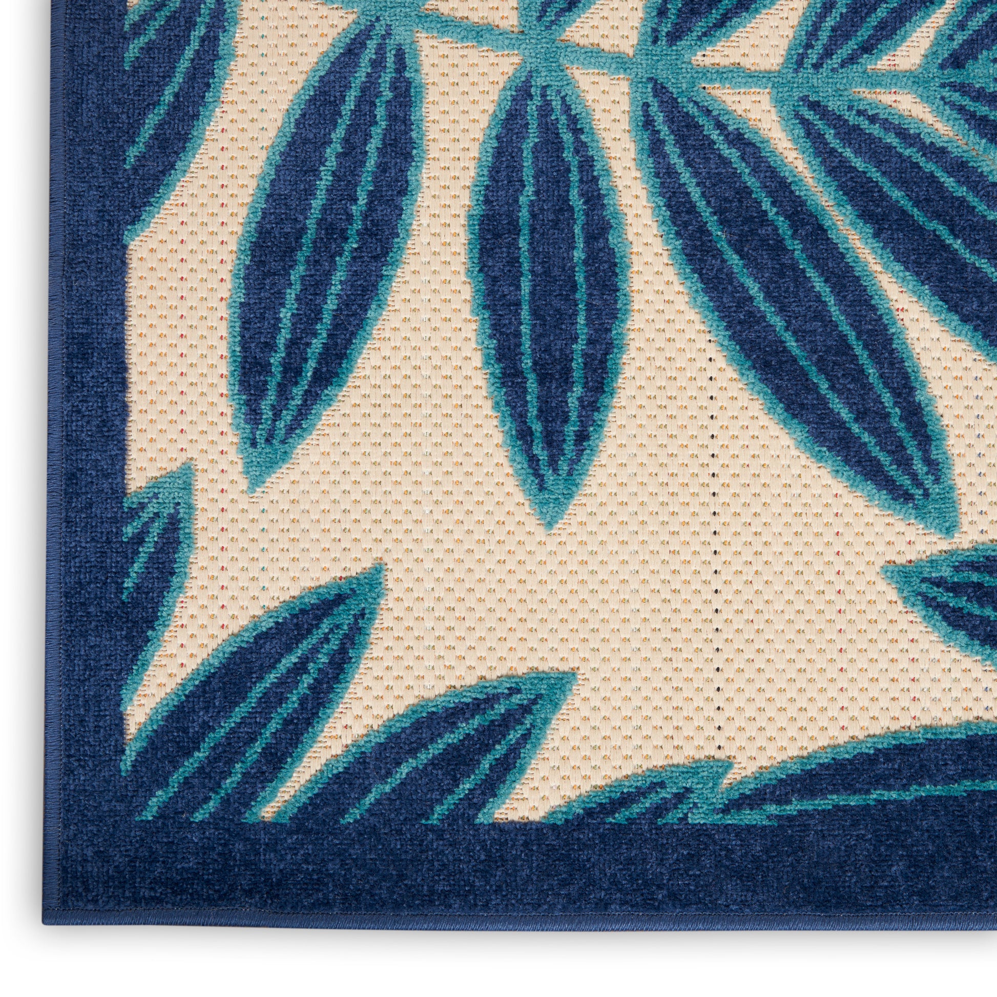 Teal palm leaf pattern on cream textured rug with navy border; outdoor rug.