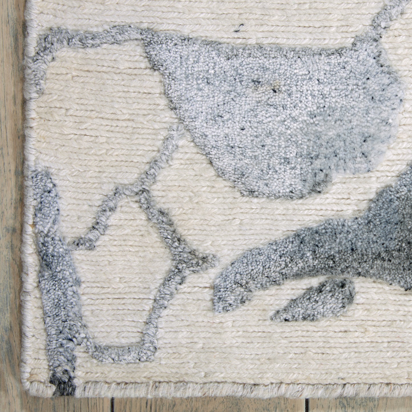 Beige textured rug with a blue-grey bird silhouette, loop pile, cozy coastal style.
