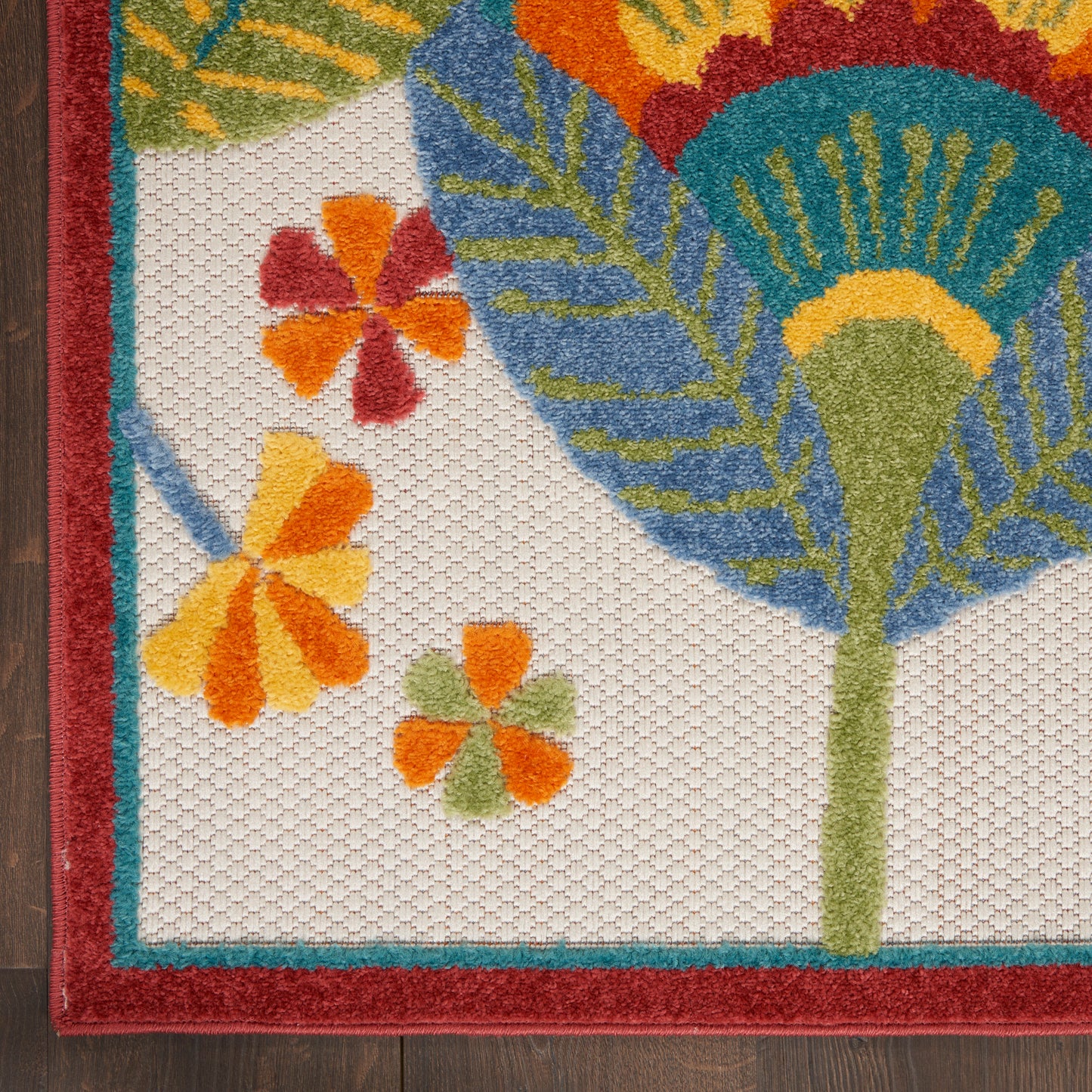 Woven rug with tropical floral motif: orange flowers, blue-green leaves, green stems, red border.