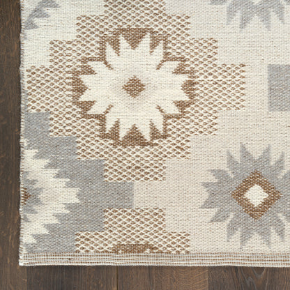 Geometric woven rug with large star motifs in beige, brown, and gray on neutral cream background, on dark wood floor.