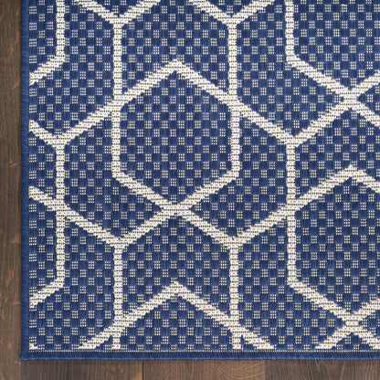 Navy blue runner rug with white geometric hexagon lattice pattern, woven texture, navy border on wood floor.