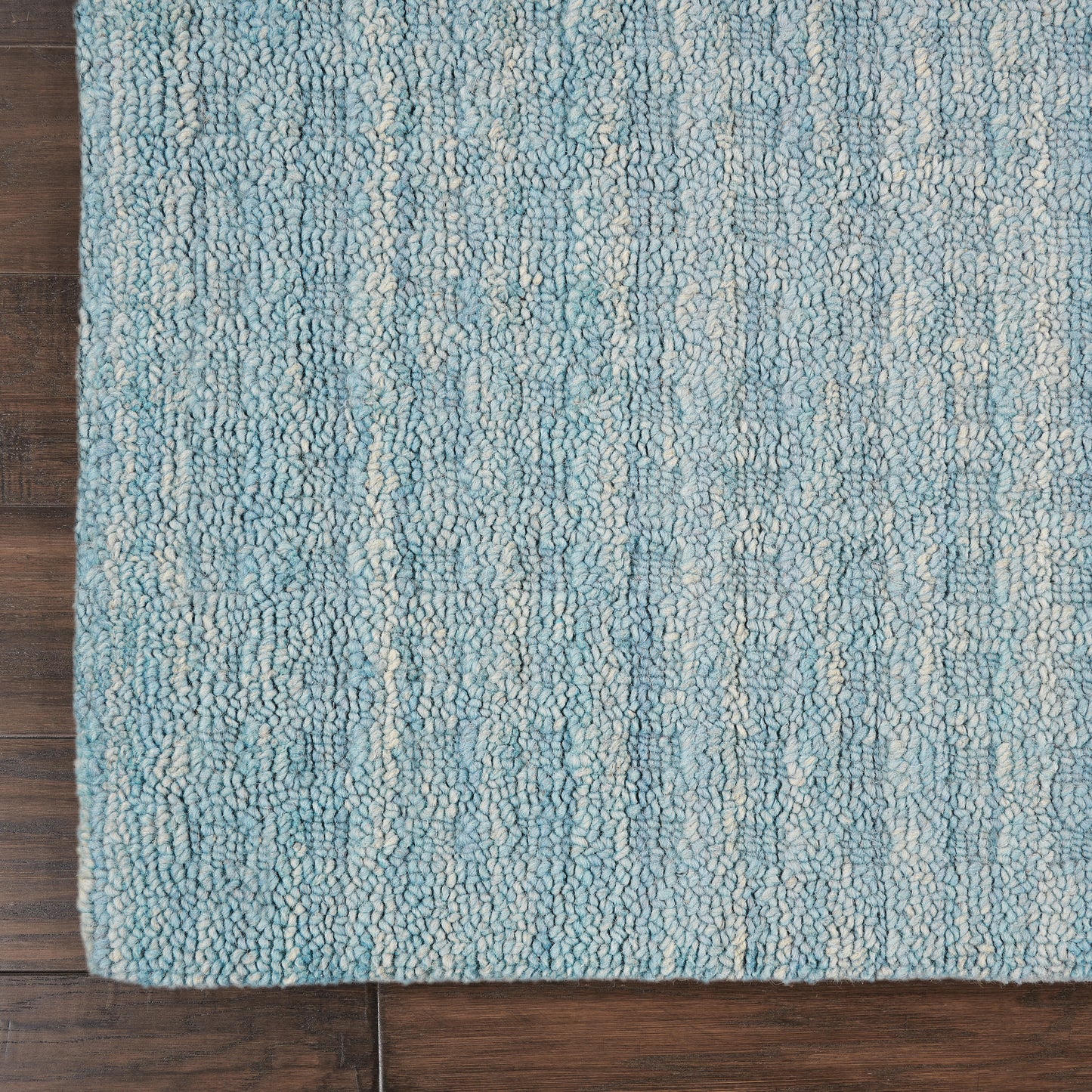 Teal-blue loop-pile rug with cream streaks on dark wood floor; rectangular, cozy coastal style.