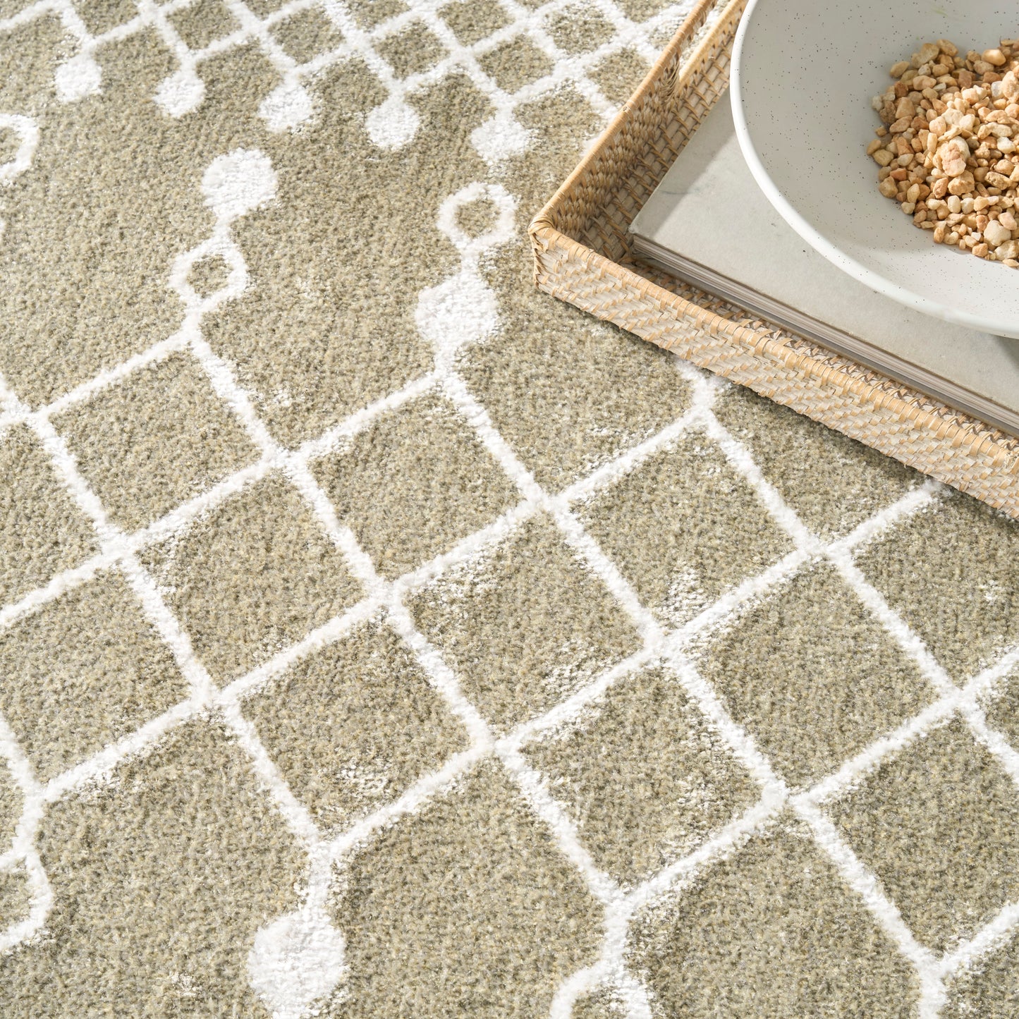 Beige shag rug with white lattice pattern; woven tray holding magazines and a ceramic bowl with granola.