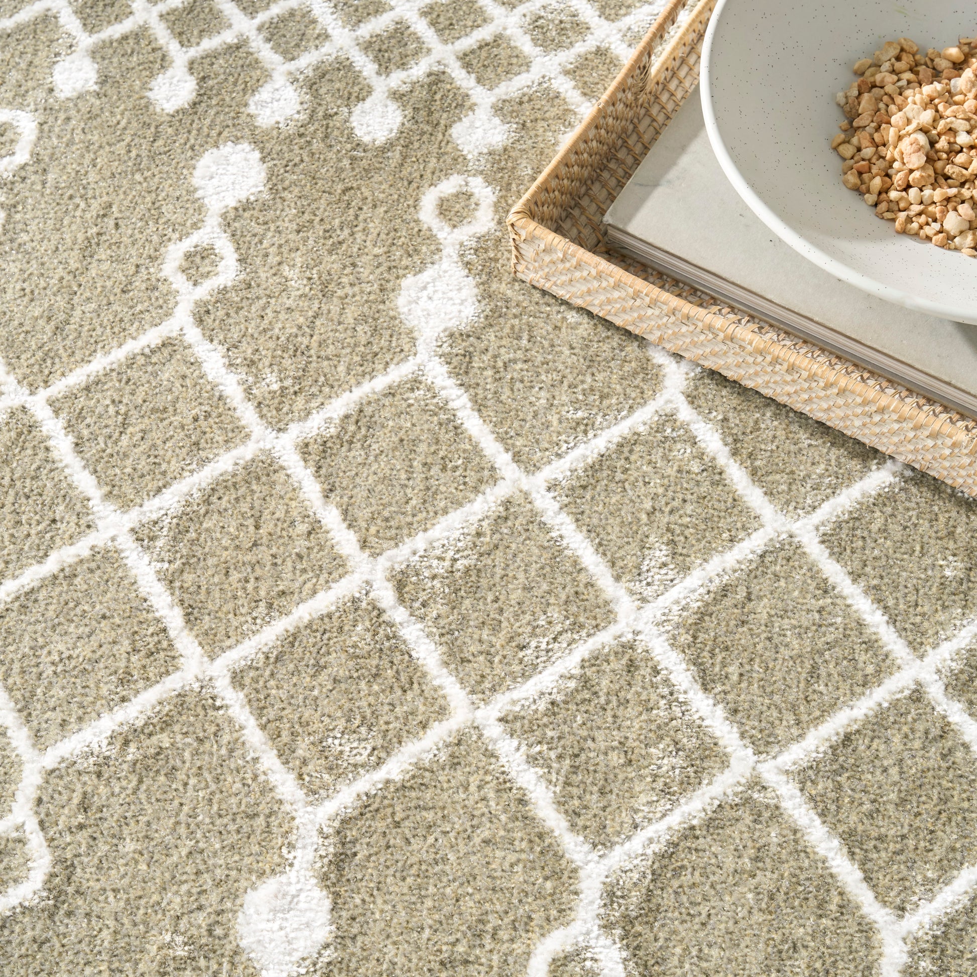 Beige shag rug with white lattice pattern; woven tray holding magazines and a ceramic bowl with granola.