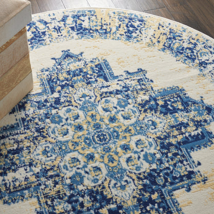Round rug with blue and cream vintage oriental pattern, distressed texture, on dark wood floor beside wooden crates.