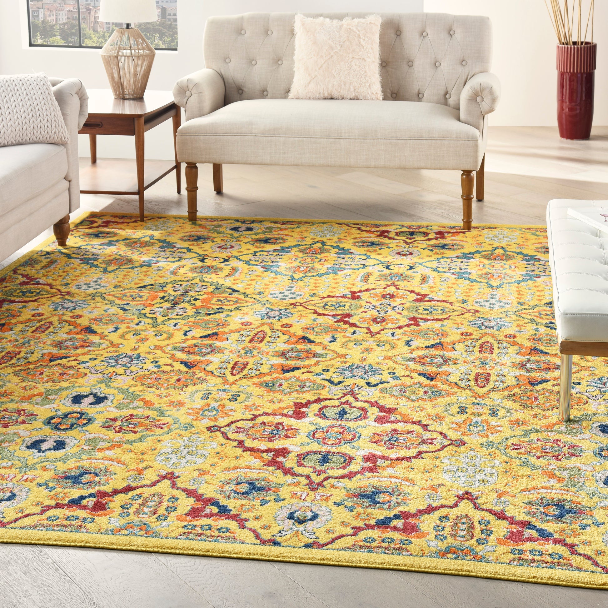 Bold yellow rectangular Persian-style area rug with red, blue, and orange floral motifs, flanked by beige tufted sofa & loveseat.