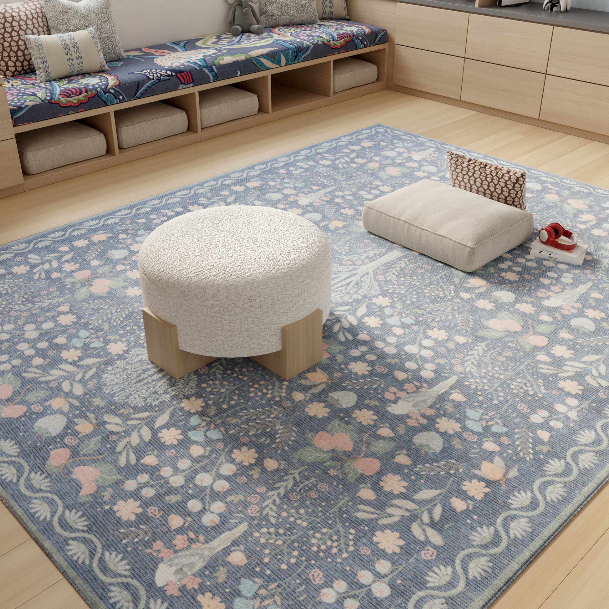 Cream boucle round ottoman with light wood legs on a blue floral area rug in a cozy living room.