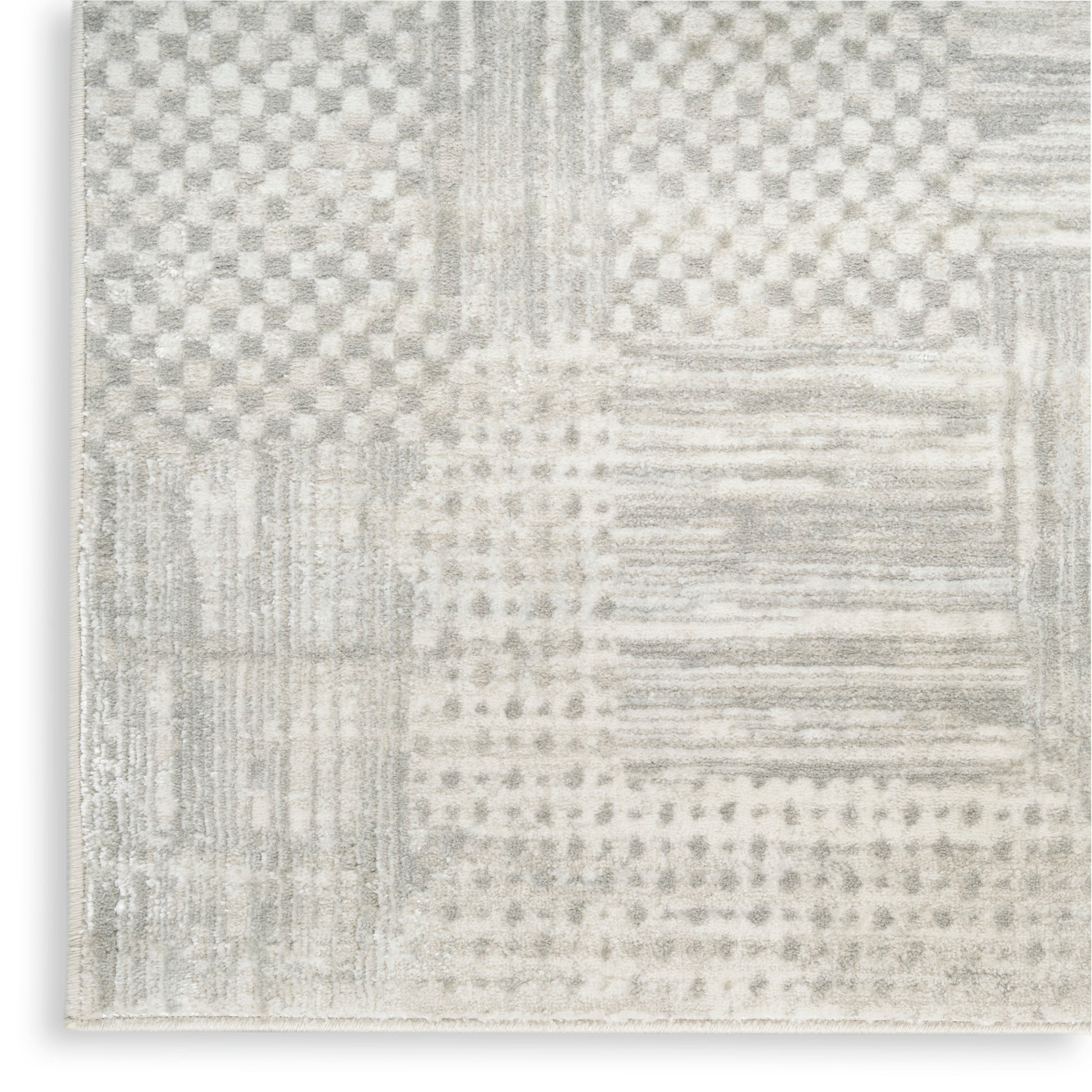 Neutral-toned patchwork rug in light gray and ivory with checkerboard, striped and dotted blocks; modern woven area rug.