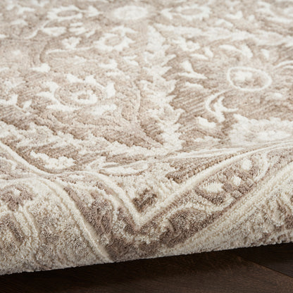 Beige ornate patterned area rug with plush pile, floral motif and decorative border on dark wood floor.
