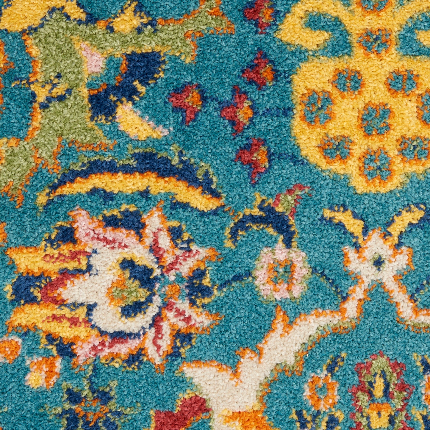 Turquoise tufted rug with bright yellow and orange floral motifs, pink accents and green vines; plush shag texture.