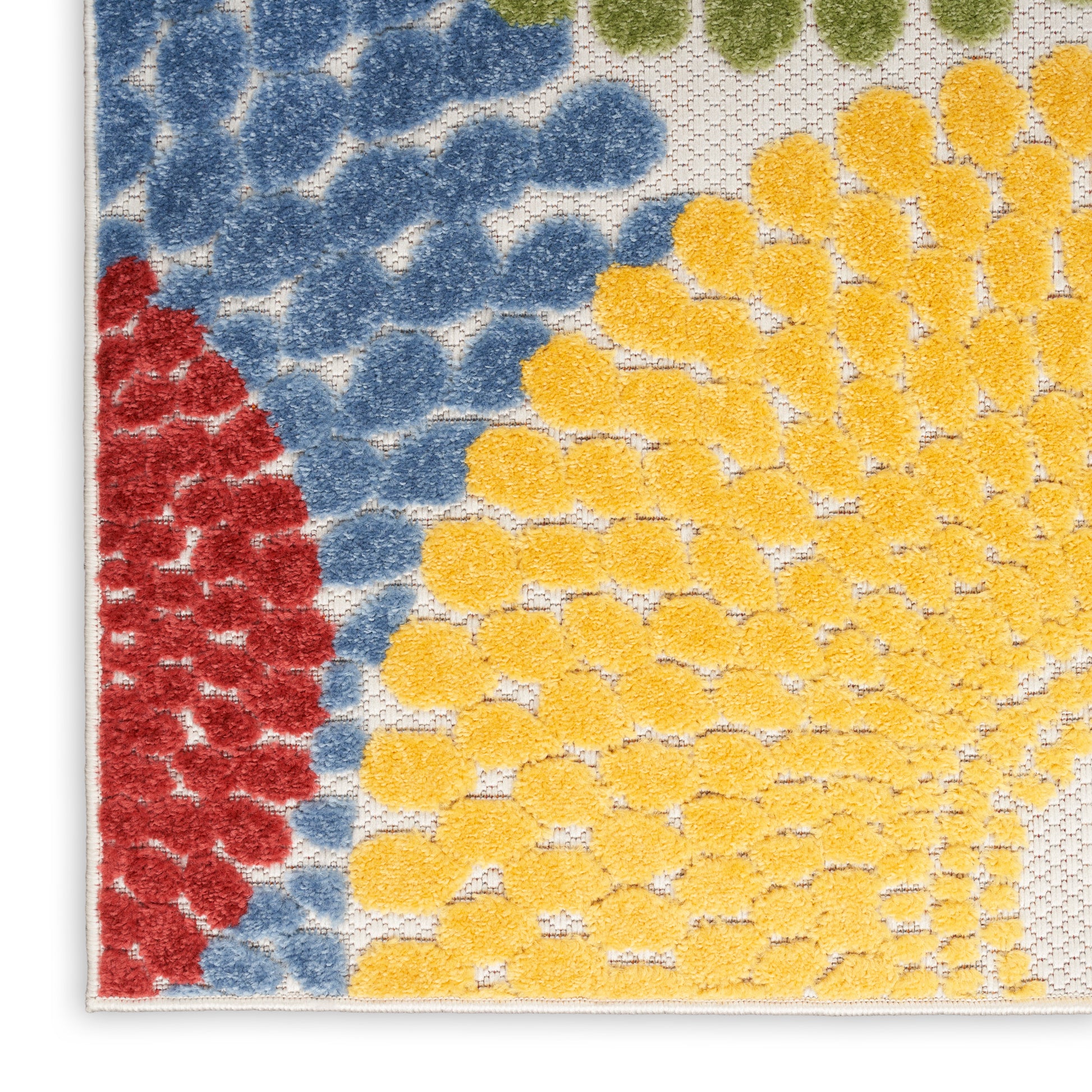 Close-up of a textured rug corner with blue and red on the left and a yellow sunburst pattern on white.