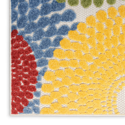 Close-up of a textured rug corner with blue and red on the left and a yellow sunburst pattern on white.