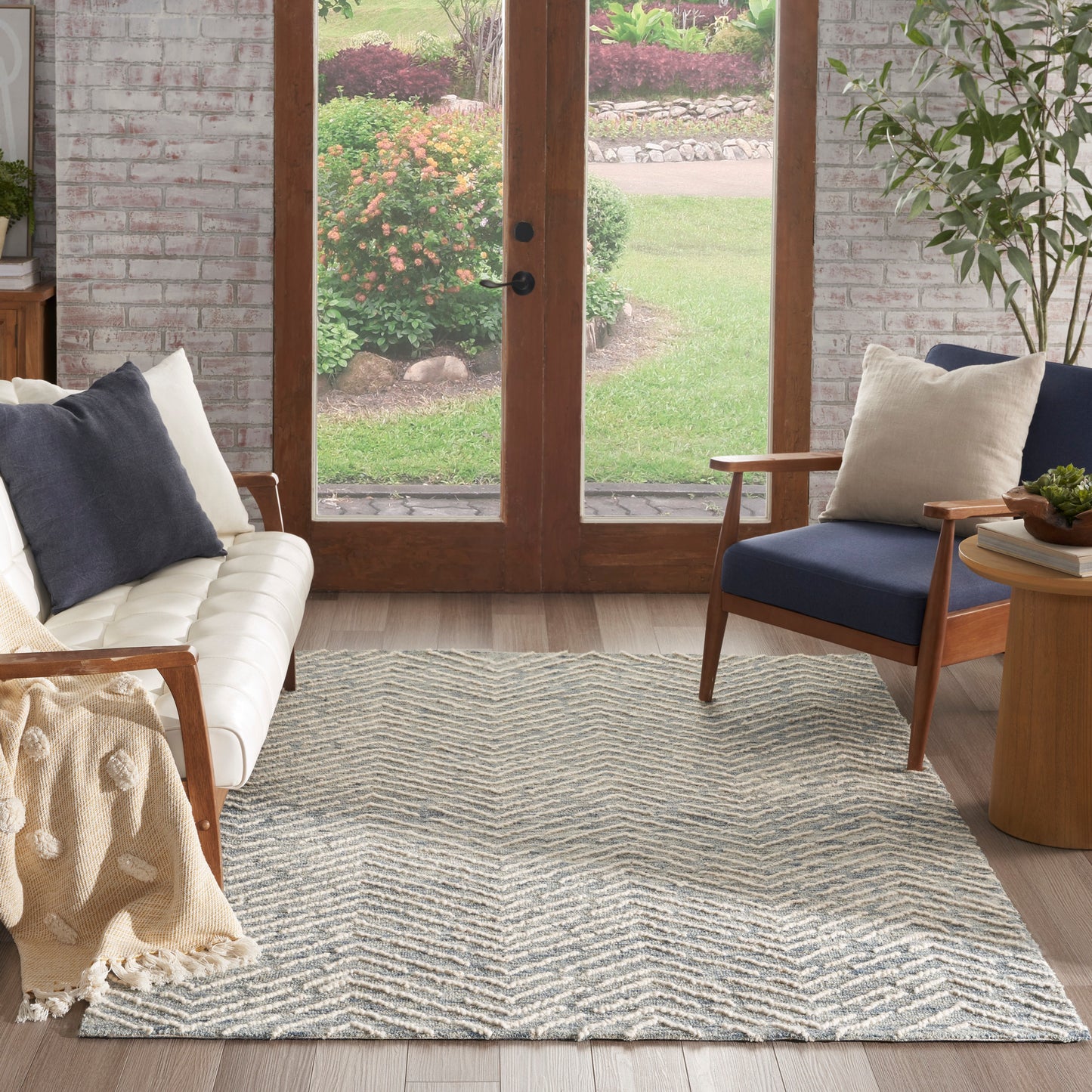Chevron-patterned light gray and white area rug in a cozy living room with wood-framed glass doors and a cream sofa.