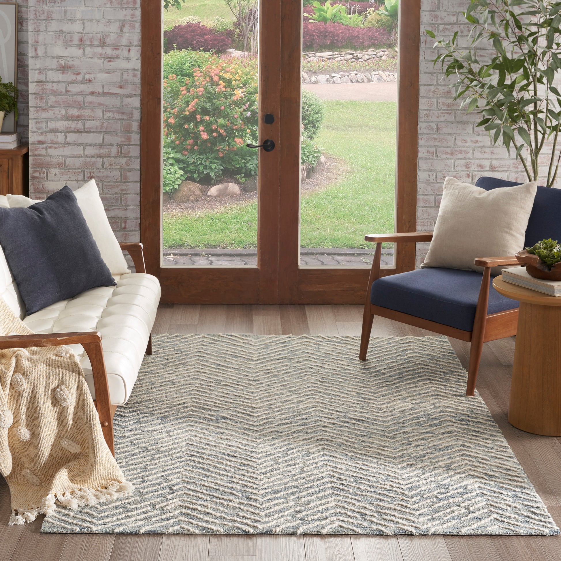 Chevron-patterned light gray and white area rug in a cozy living room with wood-framed glass doors and a cream sofa.