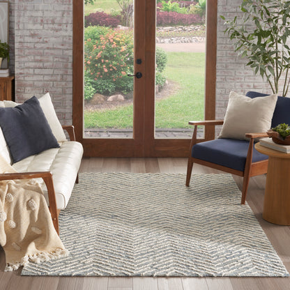 Chevron-patterned light gray and white area rug in a cozy living room with wood-framed glass doors and a cream sofa.