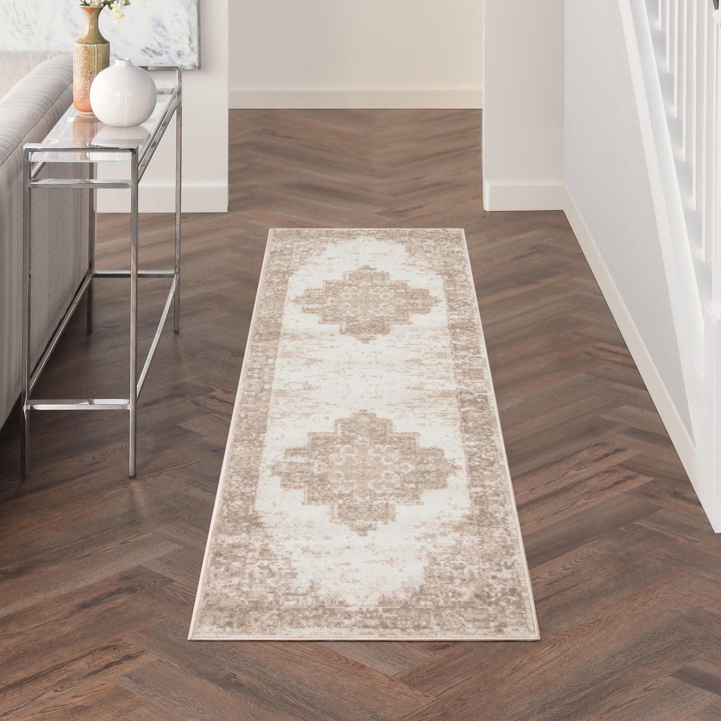 Beige ivory hallway runner rug with distressed medallion motif on dark herringbone floor