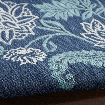 Navy blue woven textile with teal leaves and white floral motifs, folded edge visible.