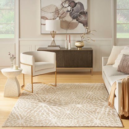 Neutral living room with cream armchair, beige sofa, light patterned rug, dark wood console & abstract art.