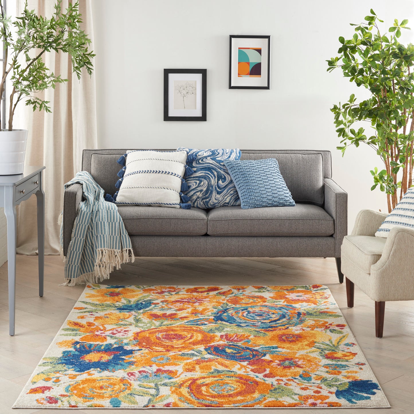 Cozy living room with grey sofa & blue-white cushions, striped throw, beige armchair, and a bright orange-blue floral rug.