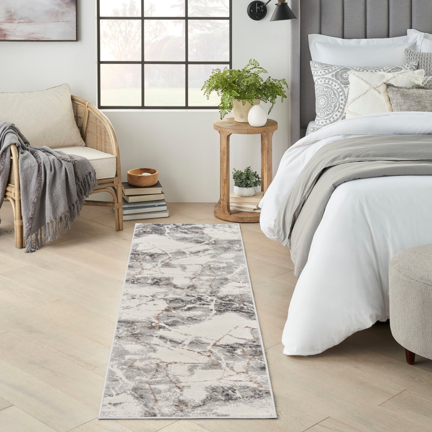 Gray and white marble-patterned runner rug on a light wood floor beside a white bed and wicker chair