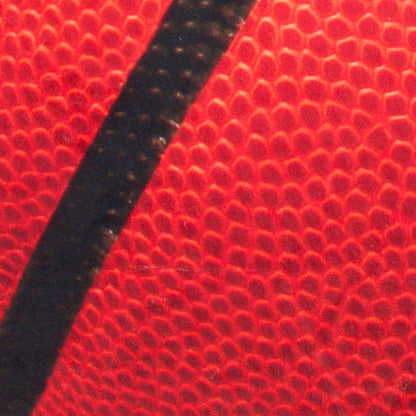Macro shot of red pebble-grain basketball with bold black seam.