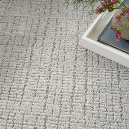 Light gray patterned rug with a white rectangular tray holding a blue-gray book and pink flowers.