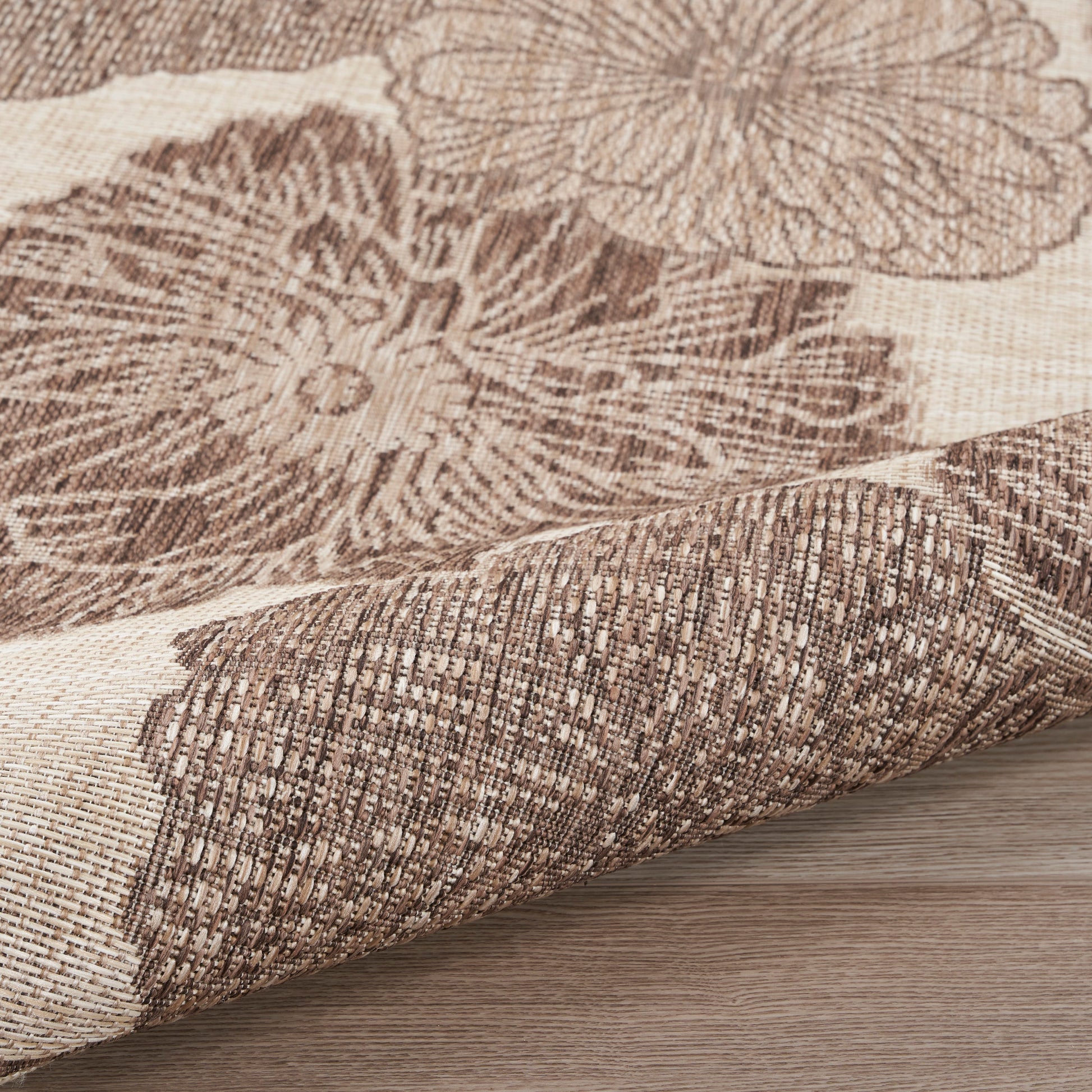 Beige and brown floral woven rug, rolled at edge; rustic textured textile for living room décor