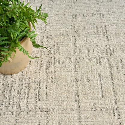 Beige ceramic pot with lush green fern on a light beige textured rug featuring geometric patterns.