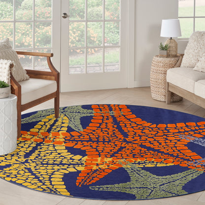 Round navy outdoor rug with a bold orange and yellow abstract pattern in a bright living room.