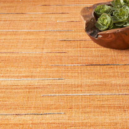 Orange woven table runner with a rounded wooden bowl of green succulents in the top-right.