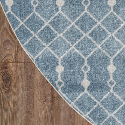 Blue area rug with white geometric lattice pattern on a brown wood floor; curved edge.