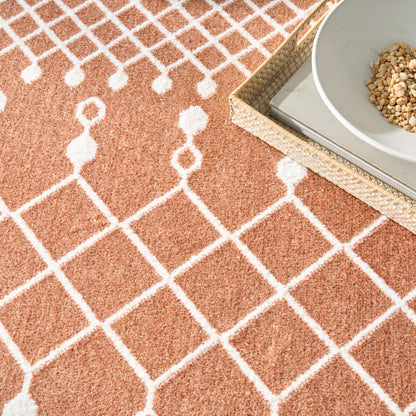 Orange rug with white diamond lattice pattern; woven basket tray & ceramic bowl of granola on top.