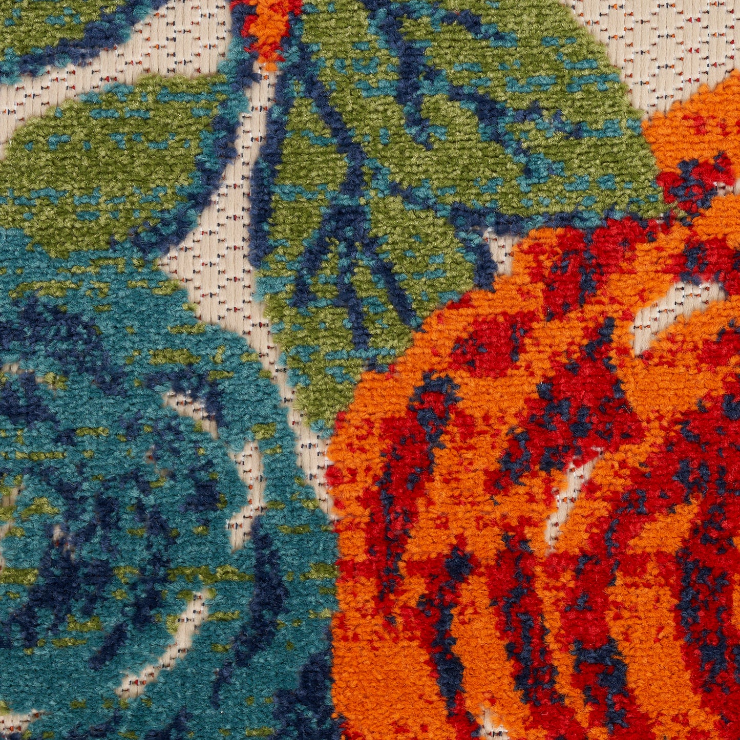 Close-up of a vibrant textured rug with blue, teal and green leaves and bold orange accents.