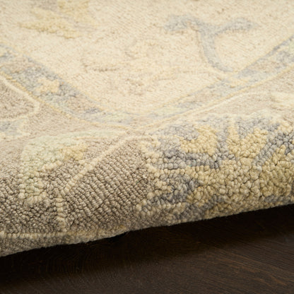 Close-up of rolled beige-gray patterned rug with soft pile on dark wood floor.