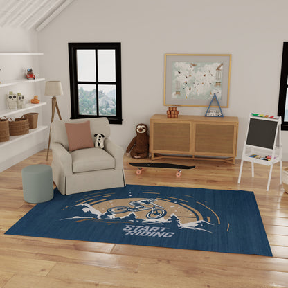 Kids' playroom with navy rug featuring a bicycle graphic and START RIDING, beige armchair, panda plush, lightwood cabinet.