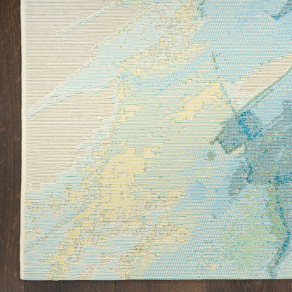 Pastel map-pattern area rug in light blues and creams, woven texture, edge on dark wood floor.
