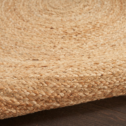 Round natural jute rug with chunky woven texture in warm beige; coastal rustic style.