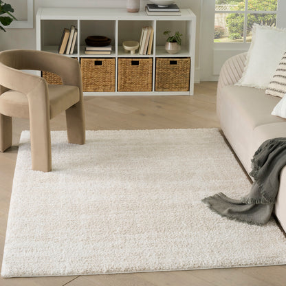 Neutral living room with a cream shag rug, beige chair, light sofa, and white cubby shelf with woven baskets.