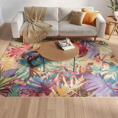 Tropical leaf rug under round wood coffee table; light gray sofa with beige throw and orange cushions.