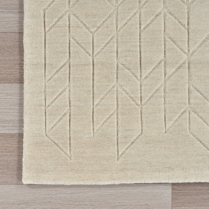 Beige flat-weave rug with raised geometric chevron/diamond pattern on light wood floor.