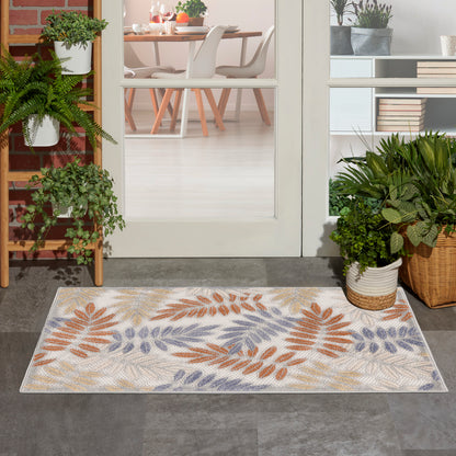 Rectangular woven rug with orange, lavender and beige leaf pattern at doorway to the dining room; potted plants nearby.