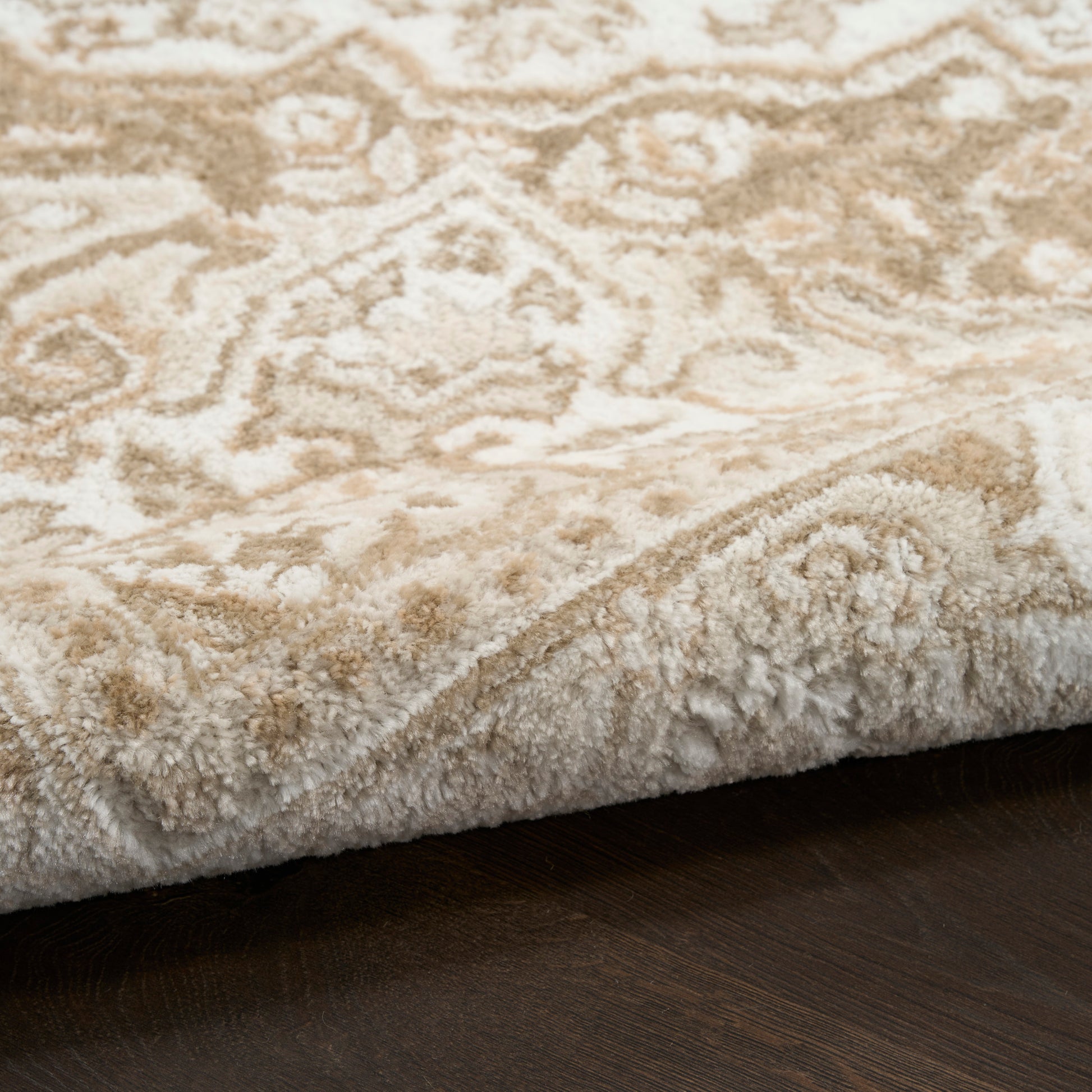 Cream and beige plush oriental rug (4' x 6') with a rolled edge and ornate pattern on dark wood floor.