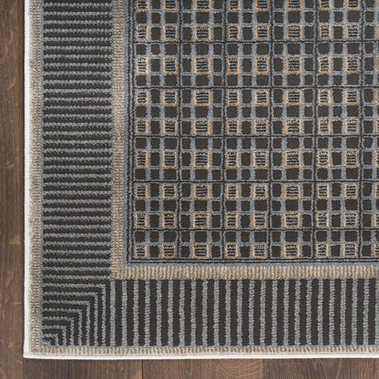 Dark gray geometric area rug with tan square accents and layered striped borders on a wooden floor.