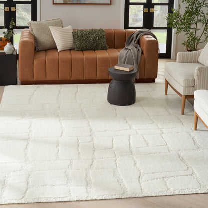 White textured area rug with grid pattern on light wood floor, paired with a tan leather sofa, gray throw, and black round side table.