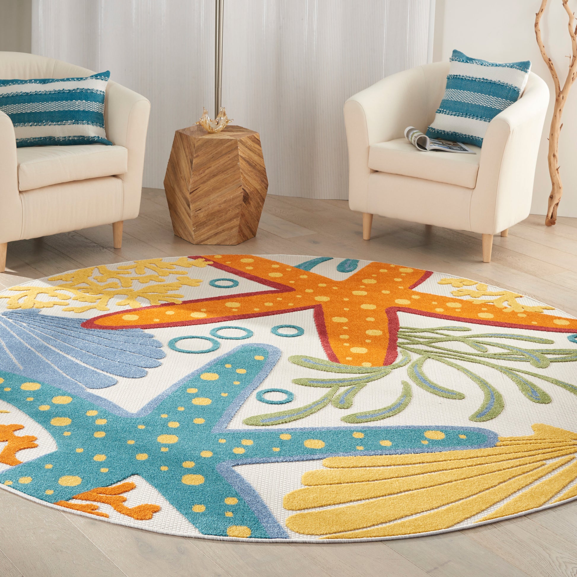 Round colorful rug with starfish design in blue, orange, yellow, & green; cream armchairs with blue striped cushions.