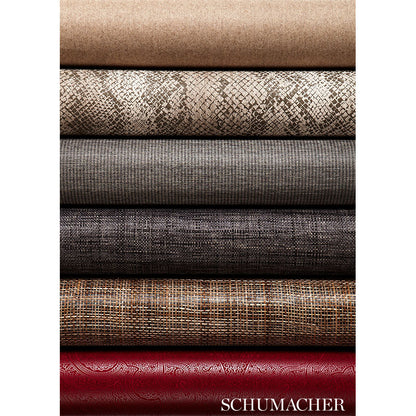 Stack of rolled sisal rug samples in beige, snakeskin, gray linen, charcoal, brown tweed, and red damask.