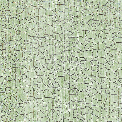 Close-up of lime-green chipped paint on weathered wooden boards with prominent cracks and a seam.