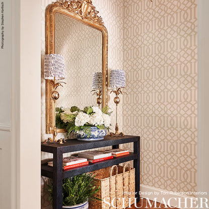 Ornate gold mirror above a dark wood console with crystal lamps, a blue-and-white porcelain vase with white flowers, and baskets.